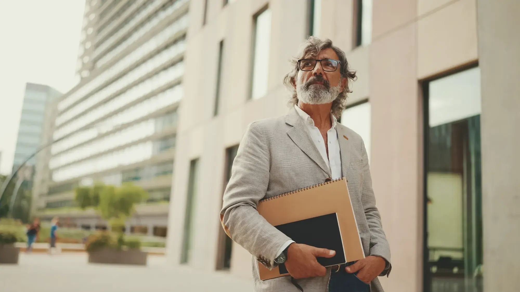 Property investor walking outside a commercial building with plans under his arm