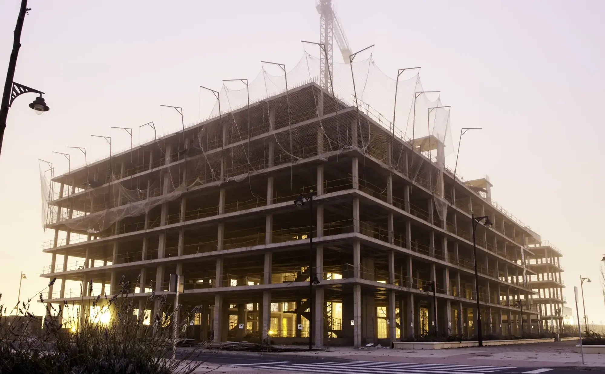 Concrete frame of a commercial building under construction with a tower crane